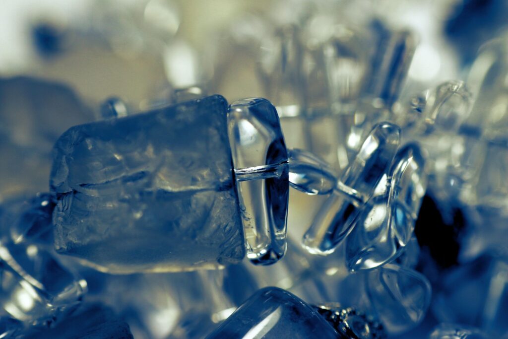 Makroaufnahme von transparentem Kristallschmuck mit kühlen Blaureflexen und weichem Bokeh.